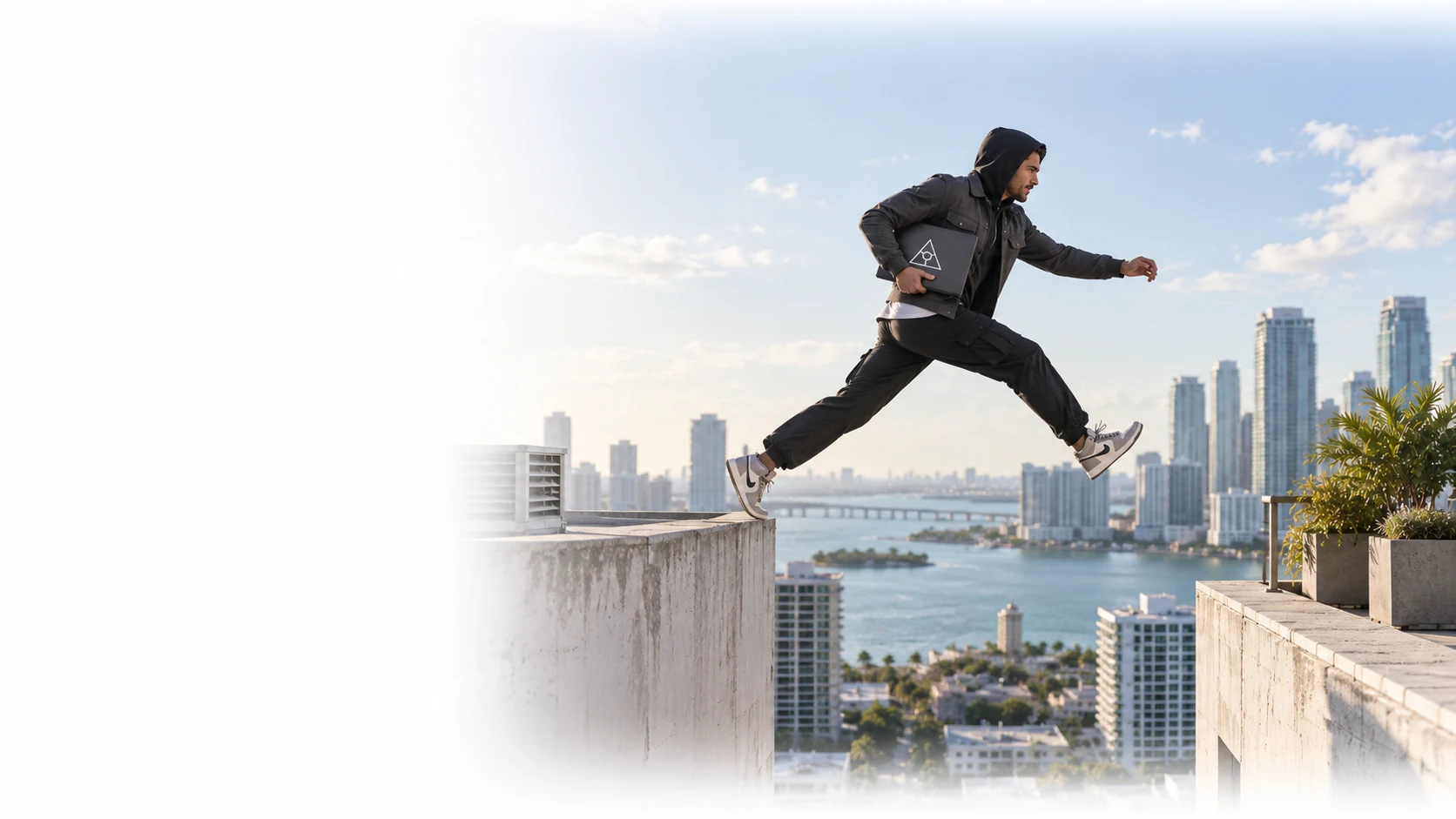 Person in dark streetwear leaping between rooftops above a waterfront city.
